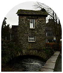 View of Bridge House in Ambleside, a 17th-century building spanning Stock Beck — representing the Ambleside Feature + Content Bundle on the Be a Guest page of Sukanya The Podcast.